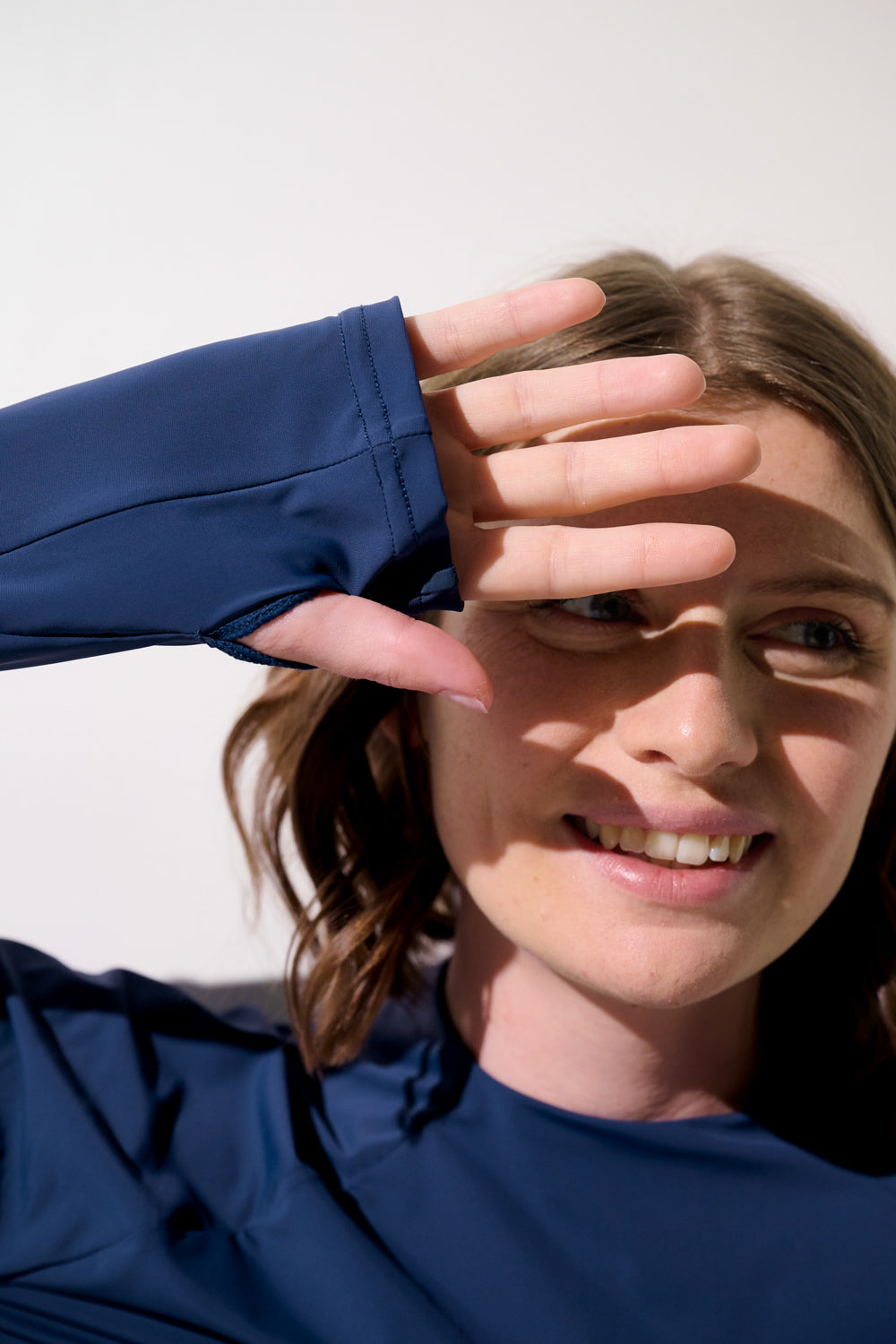 Femme souriante avec un shrug anti-UV - Sequoia bleu, protégeant des rayons du soleil avec manches longues.