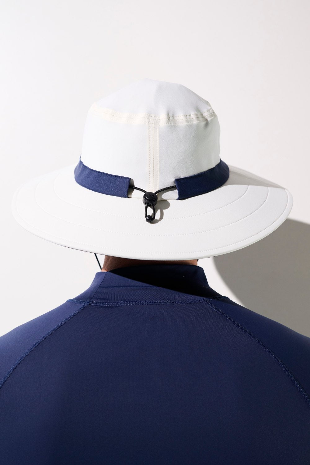 Chapeau de bain anti-UV - Galápagos, blanc et bleu, conçu pour la protection solaire avec UPF 50+, porté par homme.