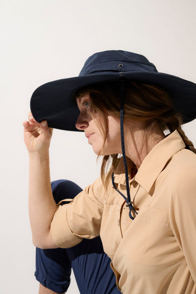 Chapeau anti-UV sombre UPF 50+ porté par une femme, idéal pour les randonnées en pleine nature.