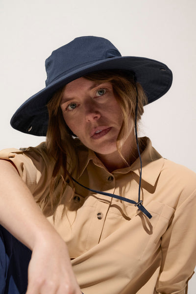 Chapeau anti-UV bleu marine UPF50+ pour femme, idéal pour randonnées en pleine nature et protection solaire.