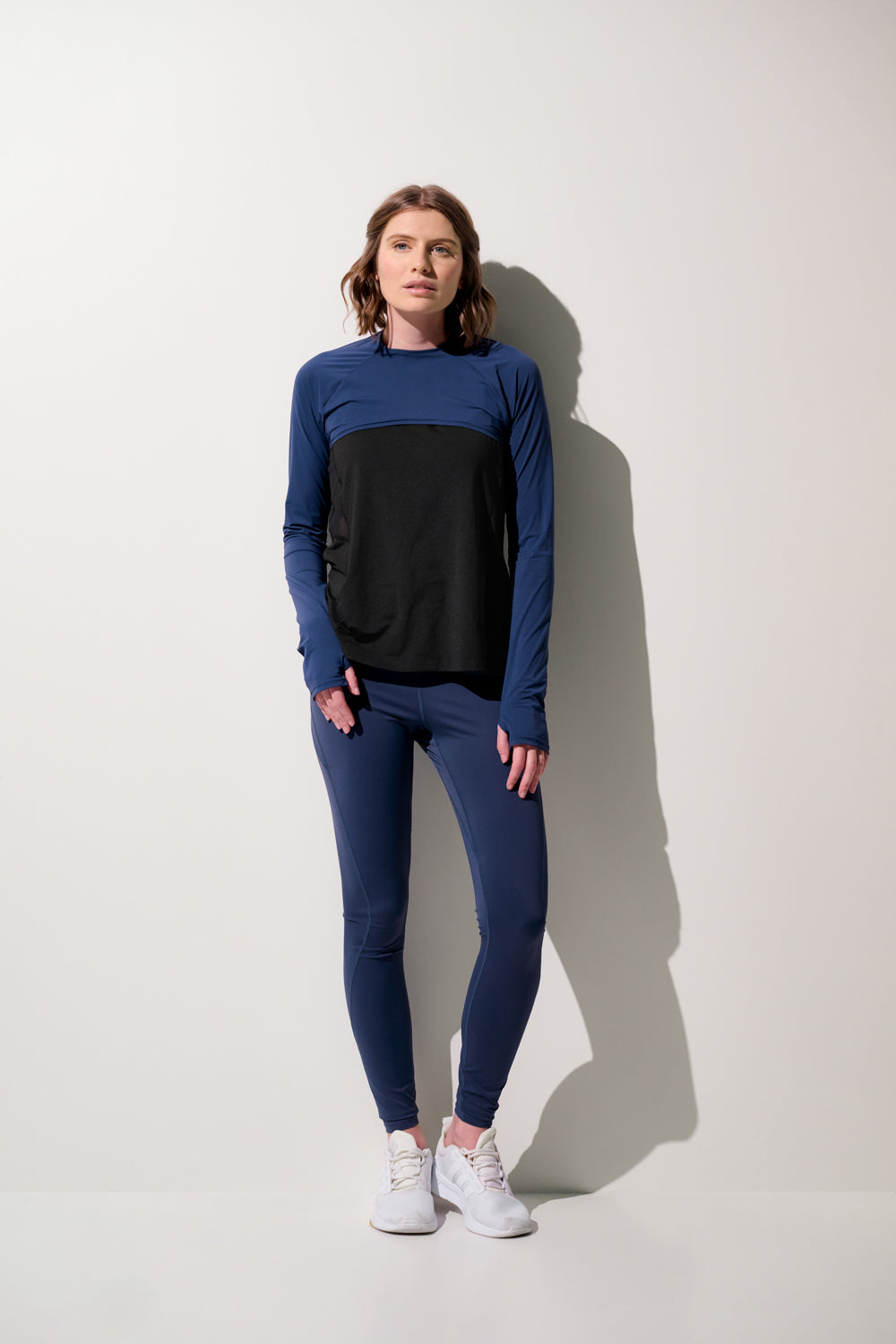 Femme portant un shrug anti-UV - Sequoia, manches longues, coloris bleu et noir, idéal pour le sport, UPF 50+.