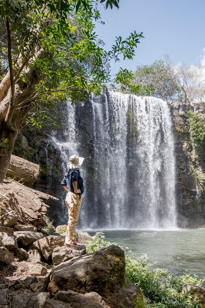 Homme admirant une cascade, portant une chemise anti-UV Ker Sun et un chapeau pour une protection solaire.