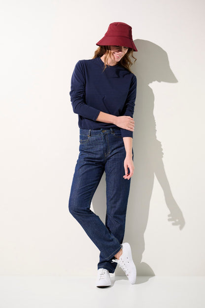 Femme portant un bob anti-UV - Faro rouge et un t-shirt marine, jeans élégants pour un style décontracté.